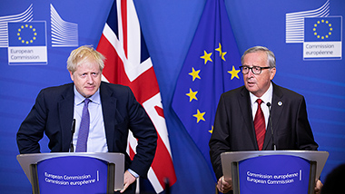 Boris Johnson and Jean-Claude Juncker, each standing at a lectern with the British and EU flags in the background