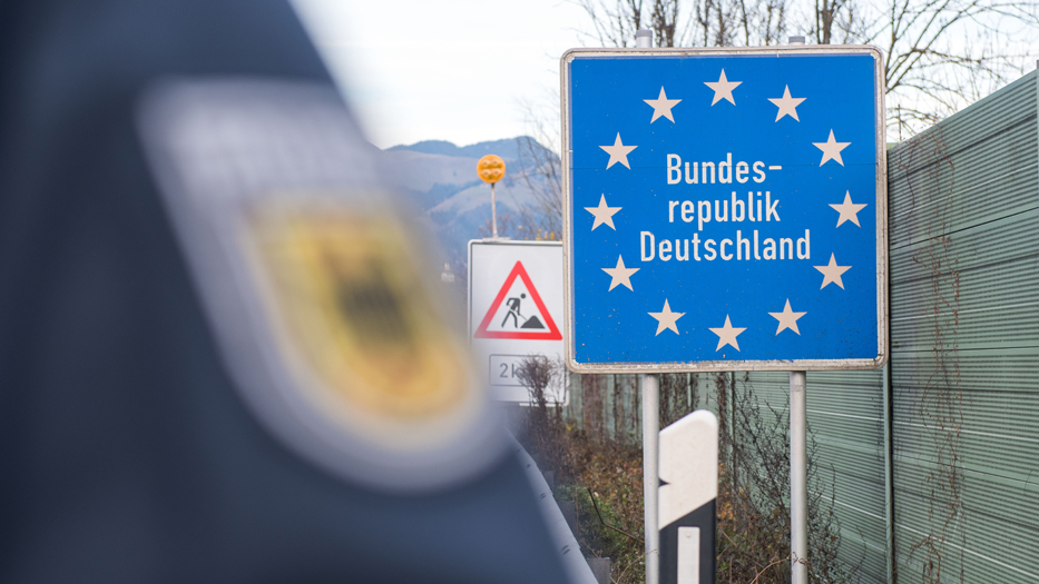 Police coat of arms with a border sign in the background