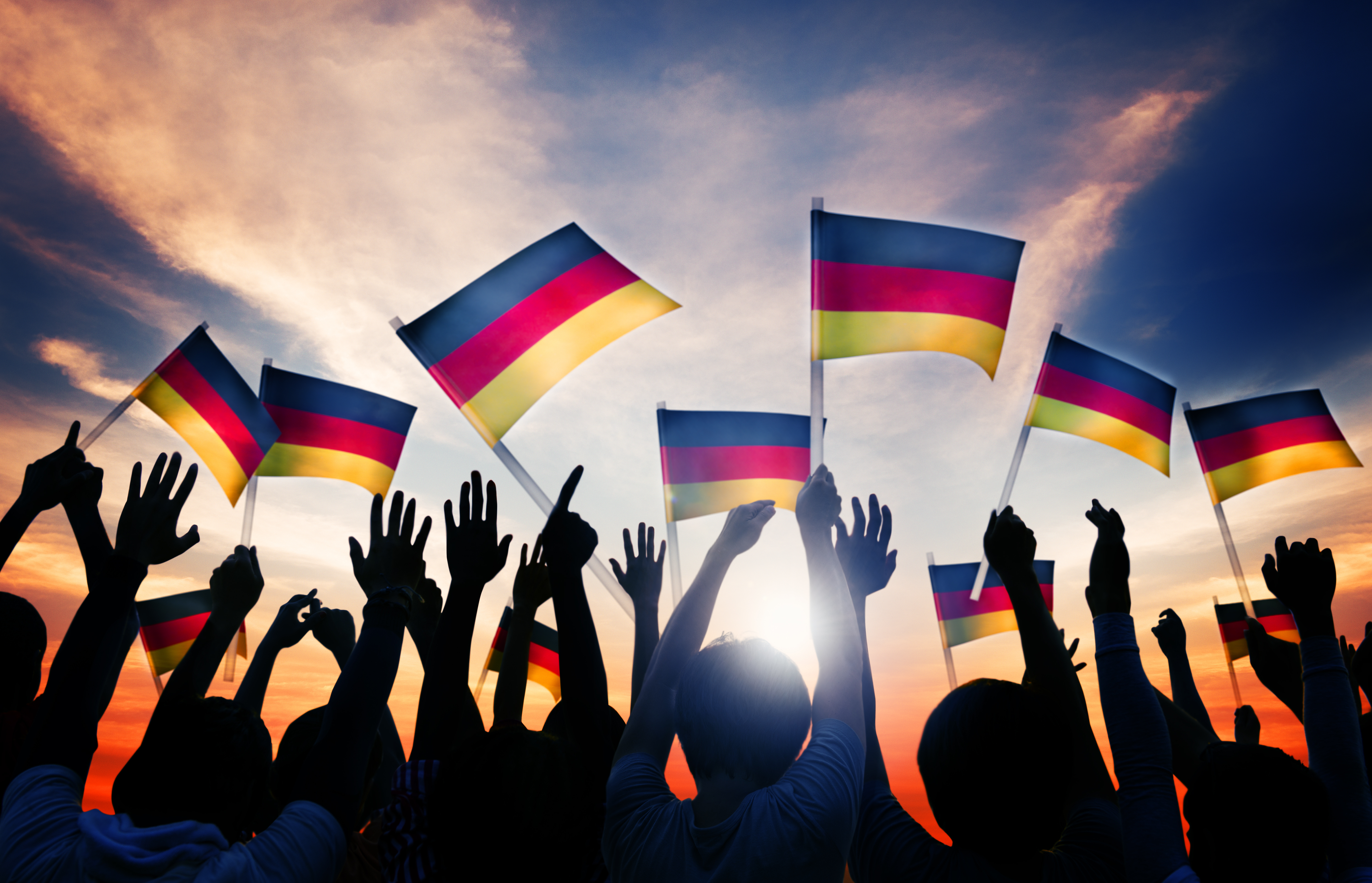 Cheering persons waving several German flags